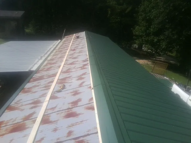 Old rusted panels beside newly installed green metal roofing — Wind Damage Roof Repair by Roofing Brothers in Lynn Center