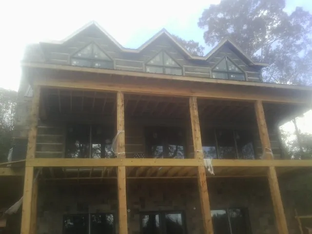 Dormers and porch framing on a large log home under construction — Roof Coating work by our crew in Lynn Center