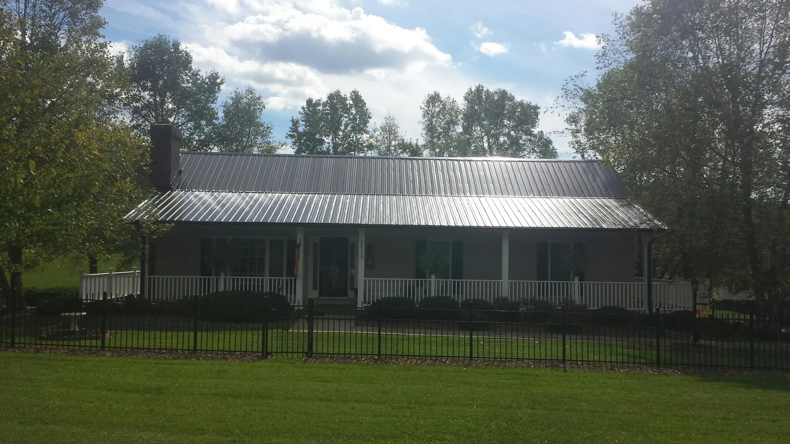 Gray metal roof on a brick ranch with a full width front porch — Gutter Guard Installation work by our crew in Lynn Center
