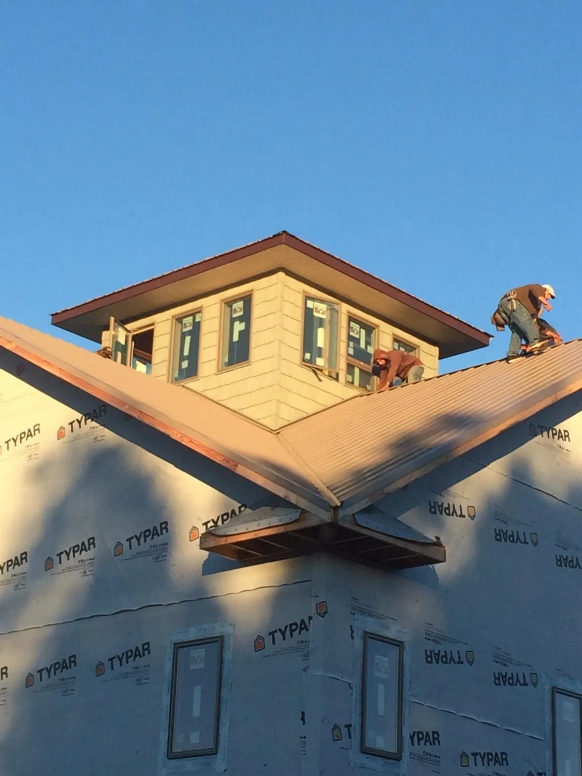 Roofers working around a rooftop cupola on a new metal roof at sunset — Roof Waterproofing in Lynn Center by Roofing Brothers